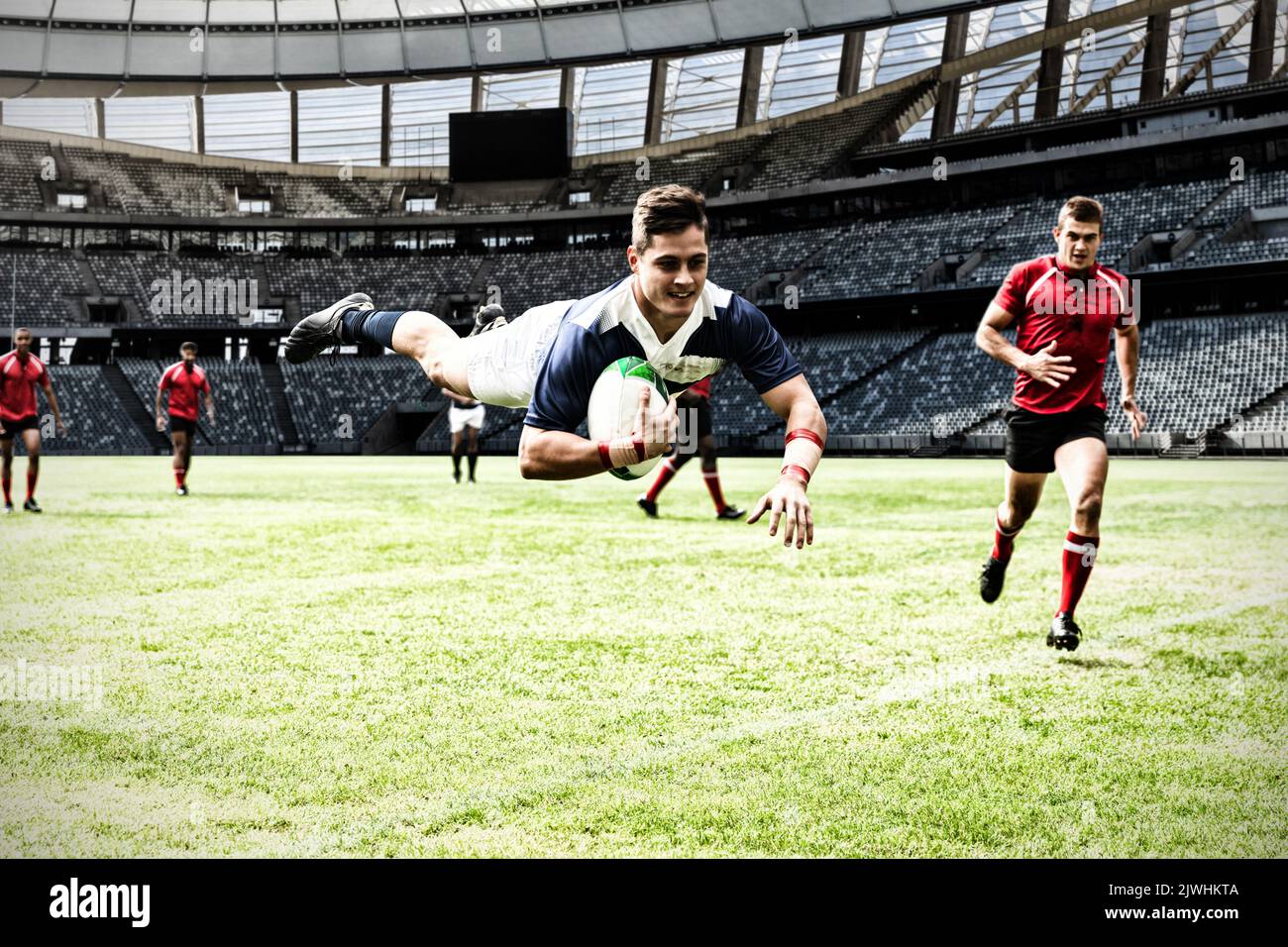 Rugby player jumping with the ball to score touchdown in sports stadium