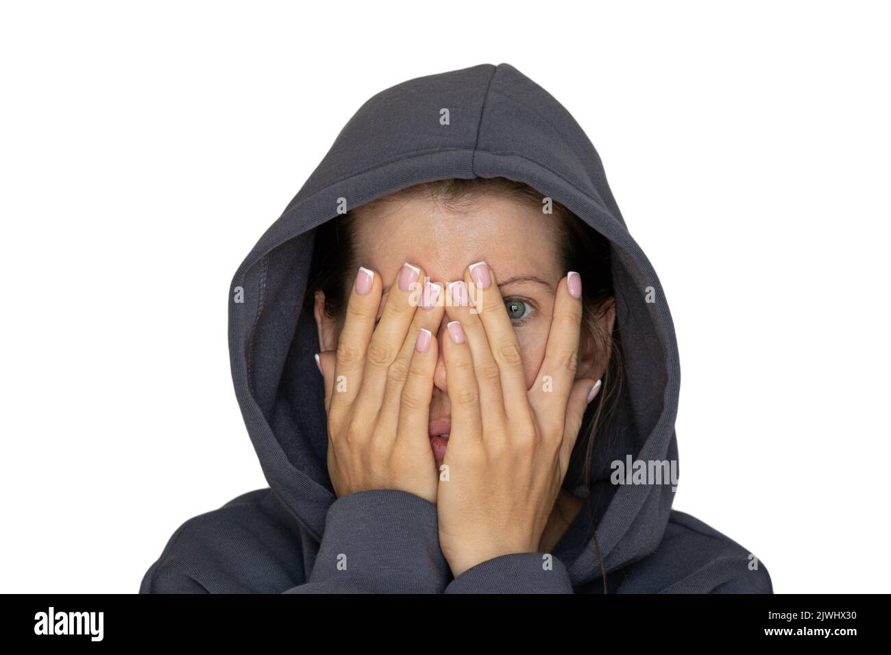 A girl in a tracksuit closes one eye with her hand on a white background, look through her hand, I see Stock Photo