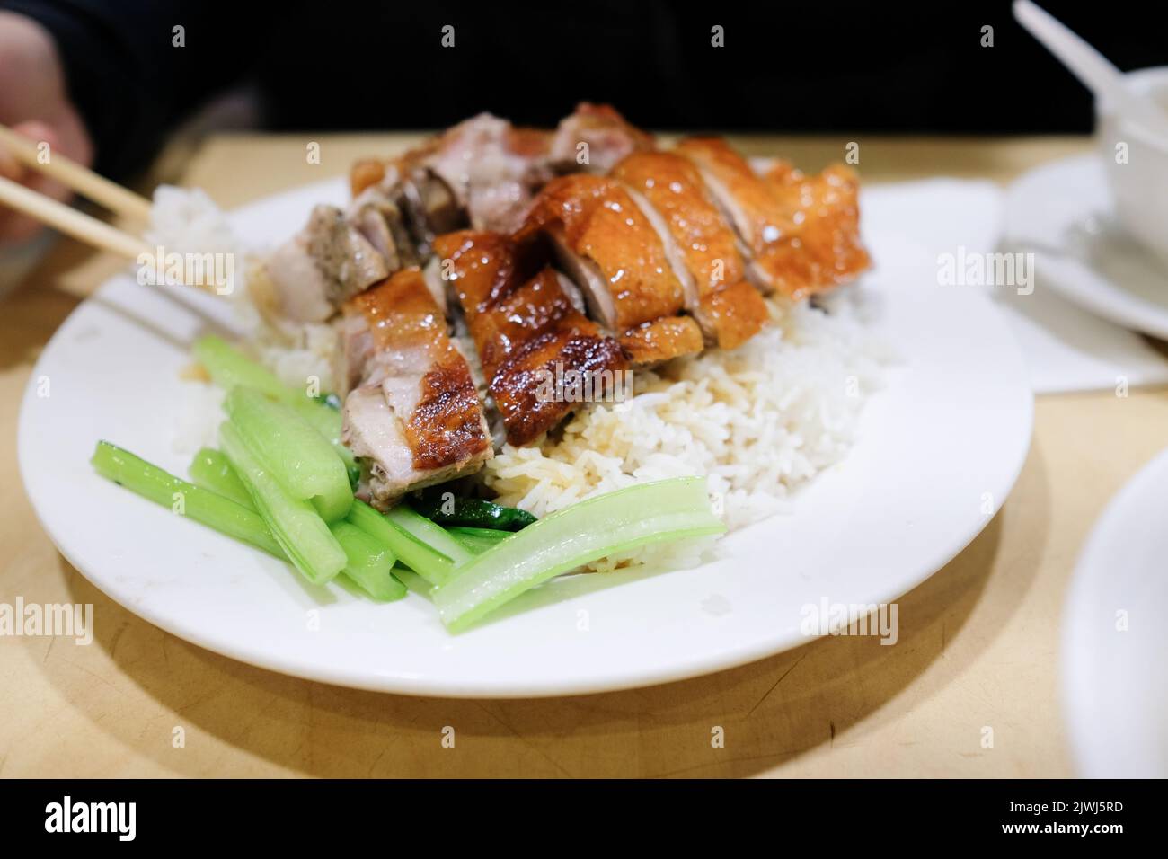 A plate of roast duck with rice and steamed greens at BBQ One, a Cantonese restaurant in