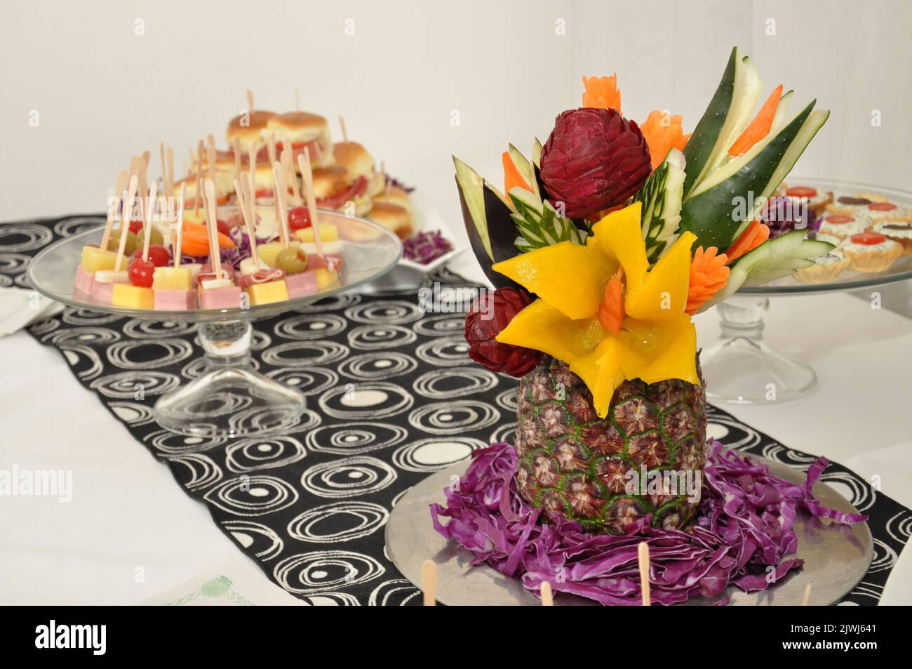 A selective focus shot of a platter of fruit skewers and pineapple art case on a dessert buffet table Stock Photo