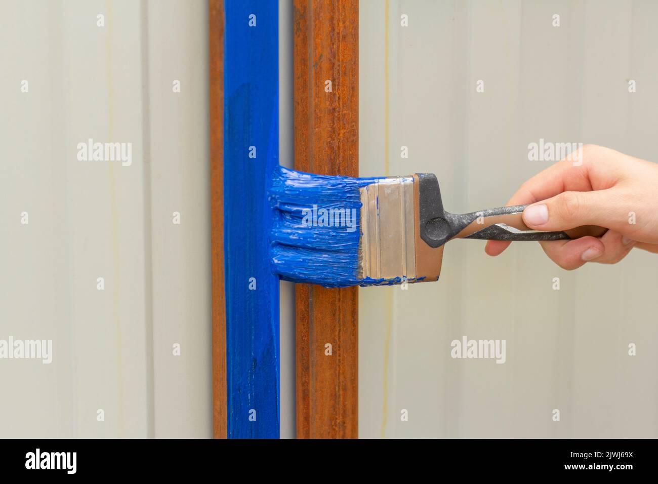 Painting rust with blue paint for metal.The hand paints the crossbars