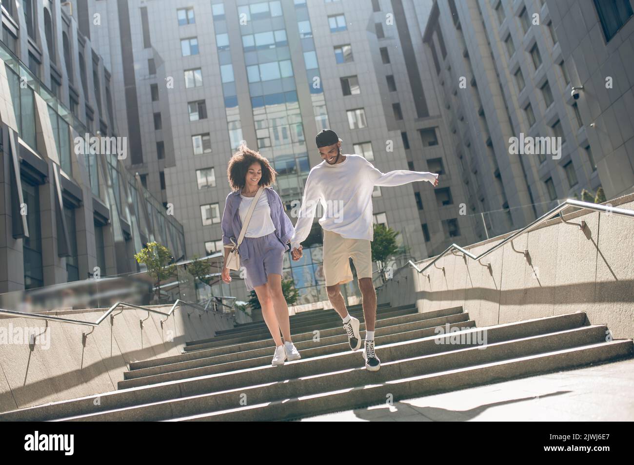 Cute couple walking hand in hand and looking happy Stock Photo - Alamy