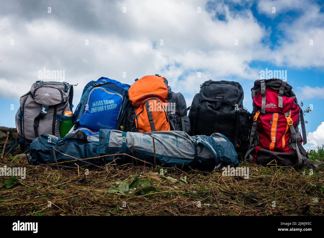 September 16th 2021. Uttarakhand India. Colorful backpacks of hikers in line in the meadows of Himalayas with landscapes in the background. Stock Photo