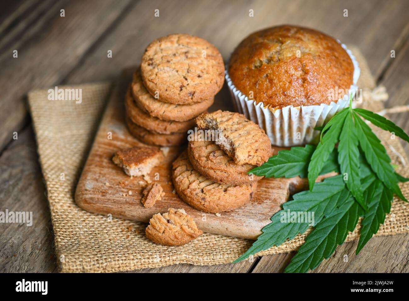 Cannabis food cookies with cake chocolate cannabis leaf marijuana herb on wooden and dark background, delicious sweet dessert cookie with hemp leaf pl Stock Photo