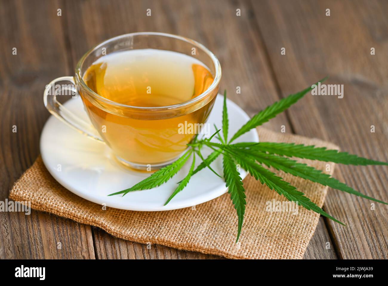 Cannabis tea herbal on tea cup with cannabis leaf marijuana leaves herb on wooden background, health tea with hemp leaf plant THC CBD herbs food and m Stock Photo