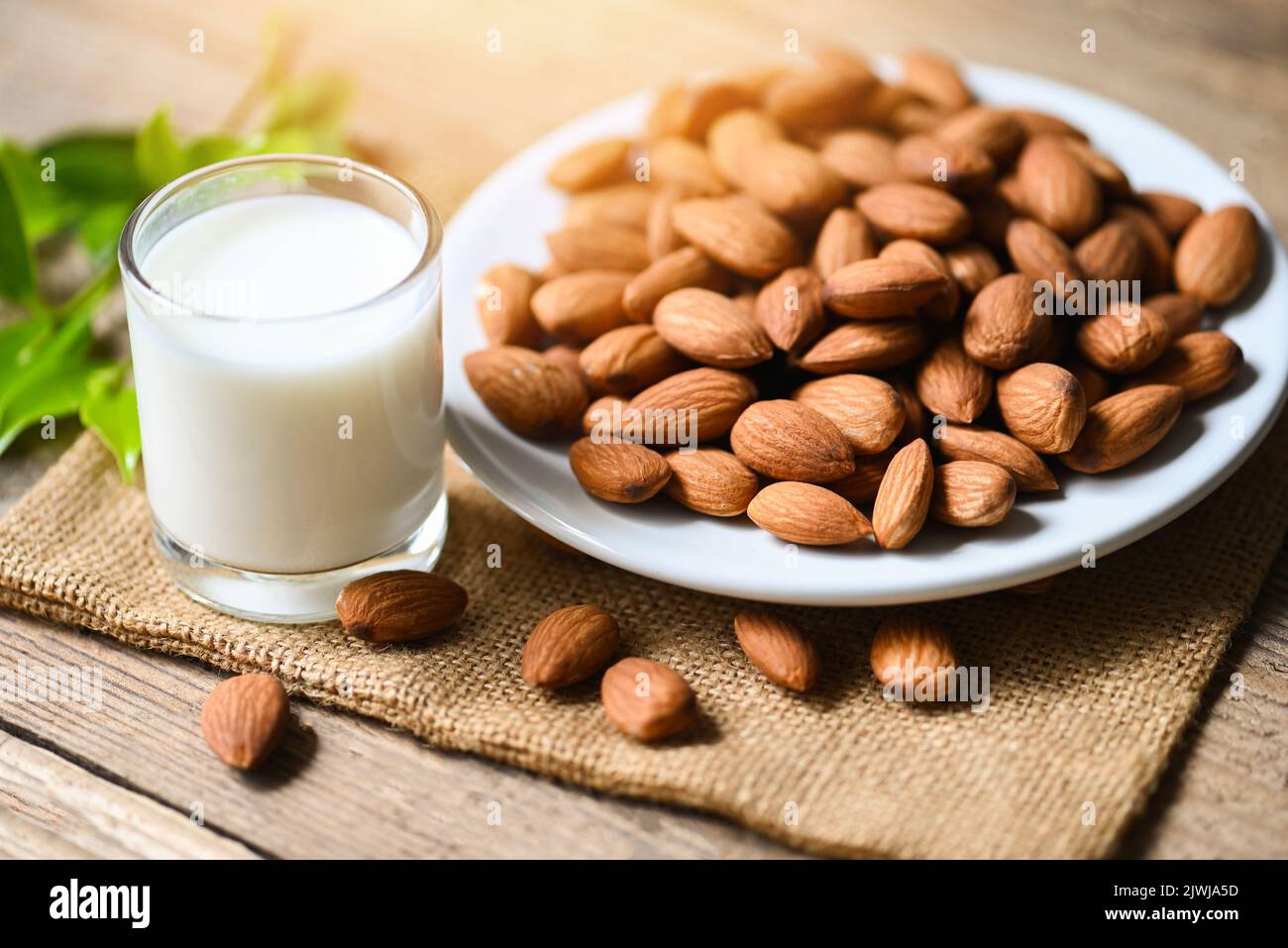 Almond milk and Almonds nuts on white plate background, Delicious sweet almonds on wooden table, roasted almond nut for healthy food and snack Stock Photo