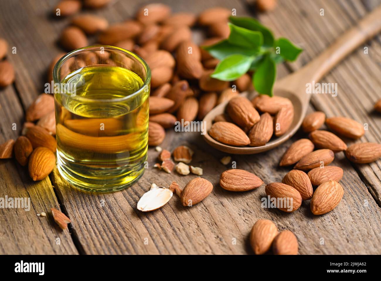 Almond oil and Almonds nuts on wooden, Delicious sweet almonds oil in glass, roasted almond nut for healthy food and snack organic vegetable oils for Stock Photo