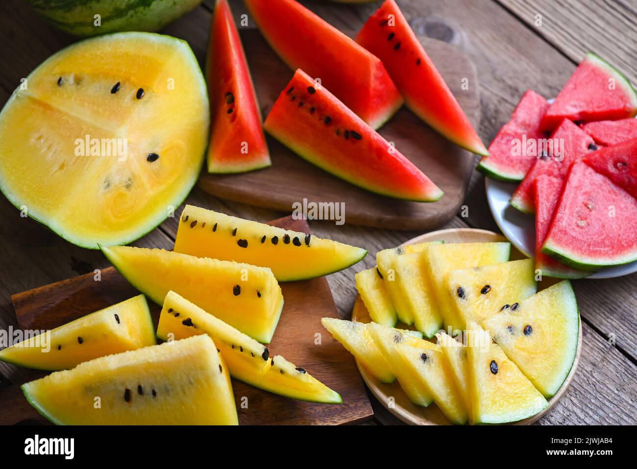 Red and yellow watermelon slice on wooden cutting board and plate, Closeup sweet watermelon slices pieces fresh watermelon tropical summer fruit - top Stock Photo