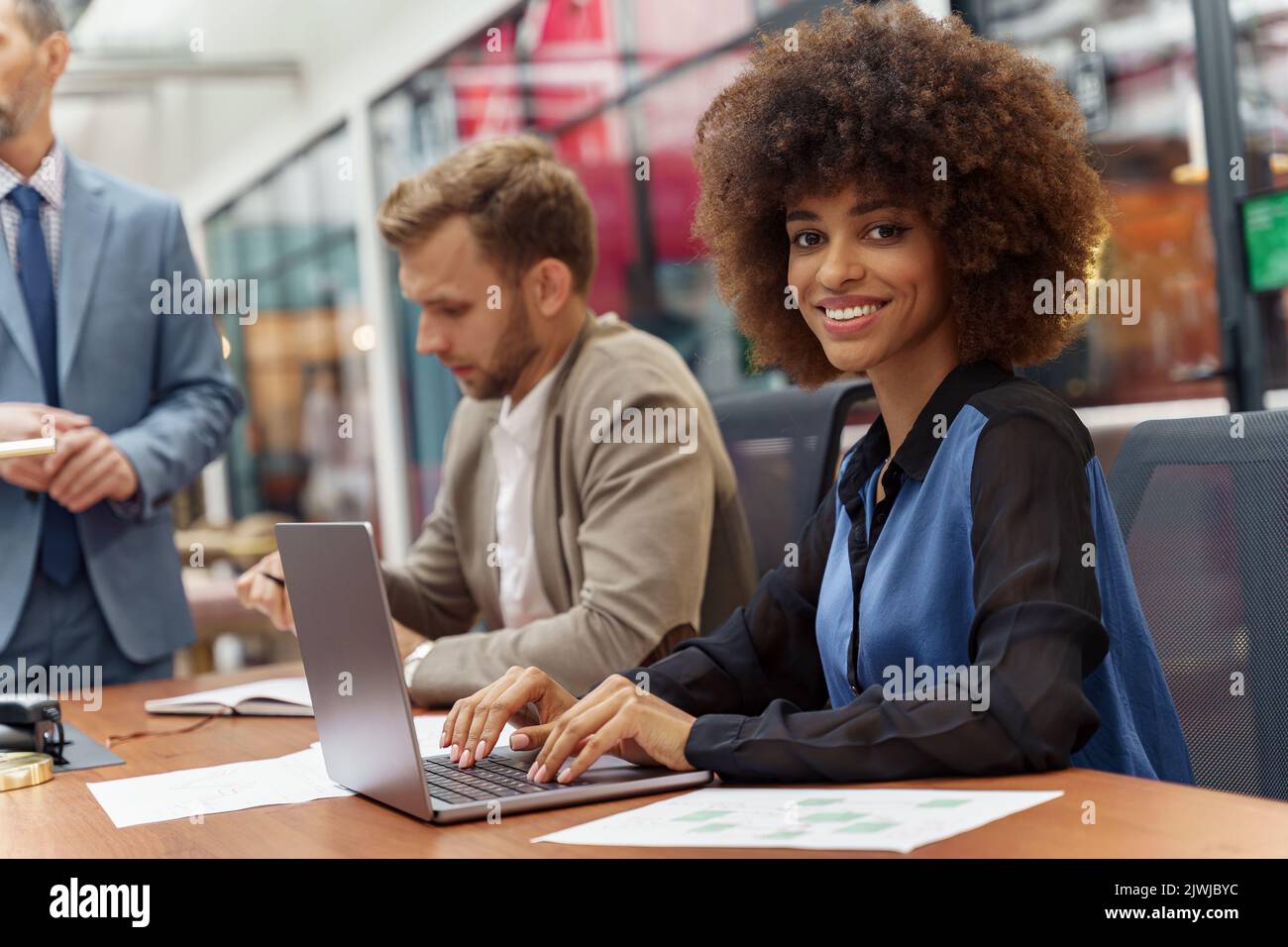 Smiling african businesswoman sitting on his workplace in modern office ...