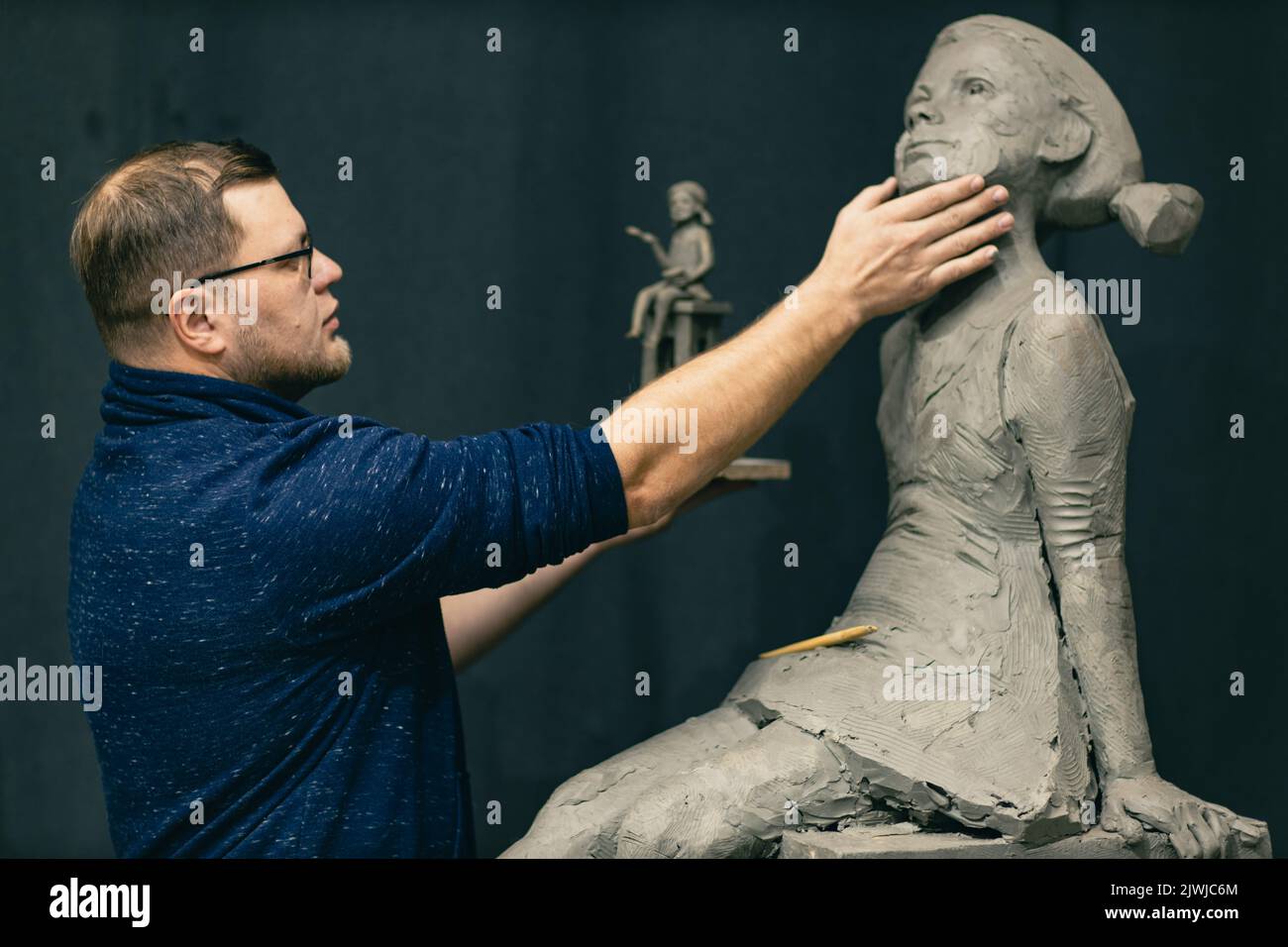 Man sculptor creates sculpt bust clay human woman sculpture. Statue