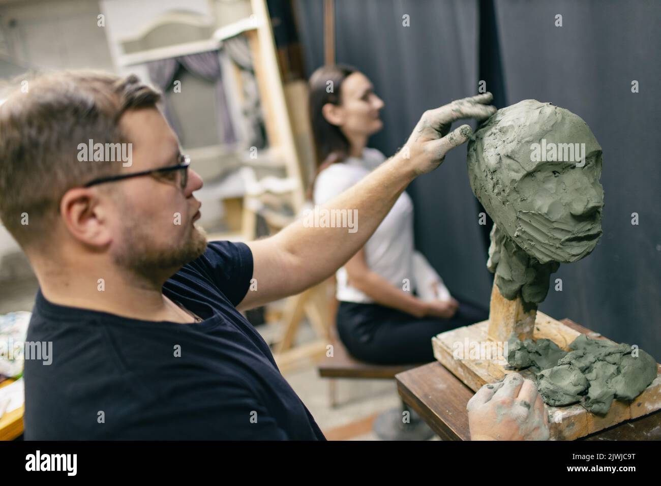 Man sculptor creates sculpt bust clay human woman sculpture. Statue