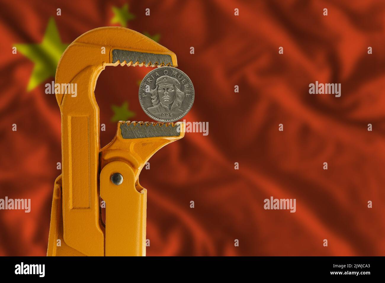 Three Cuban pesos coin held in an orange plumber wrench against the background of the flag of China. Che Guevara Stock Photo