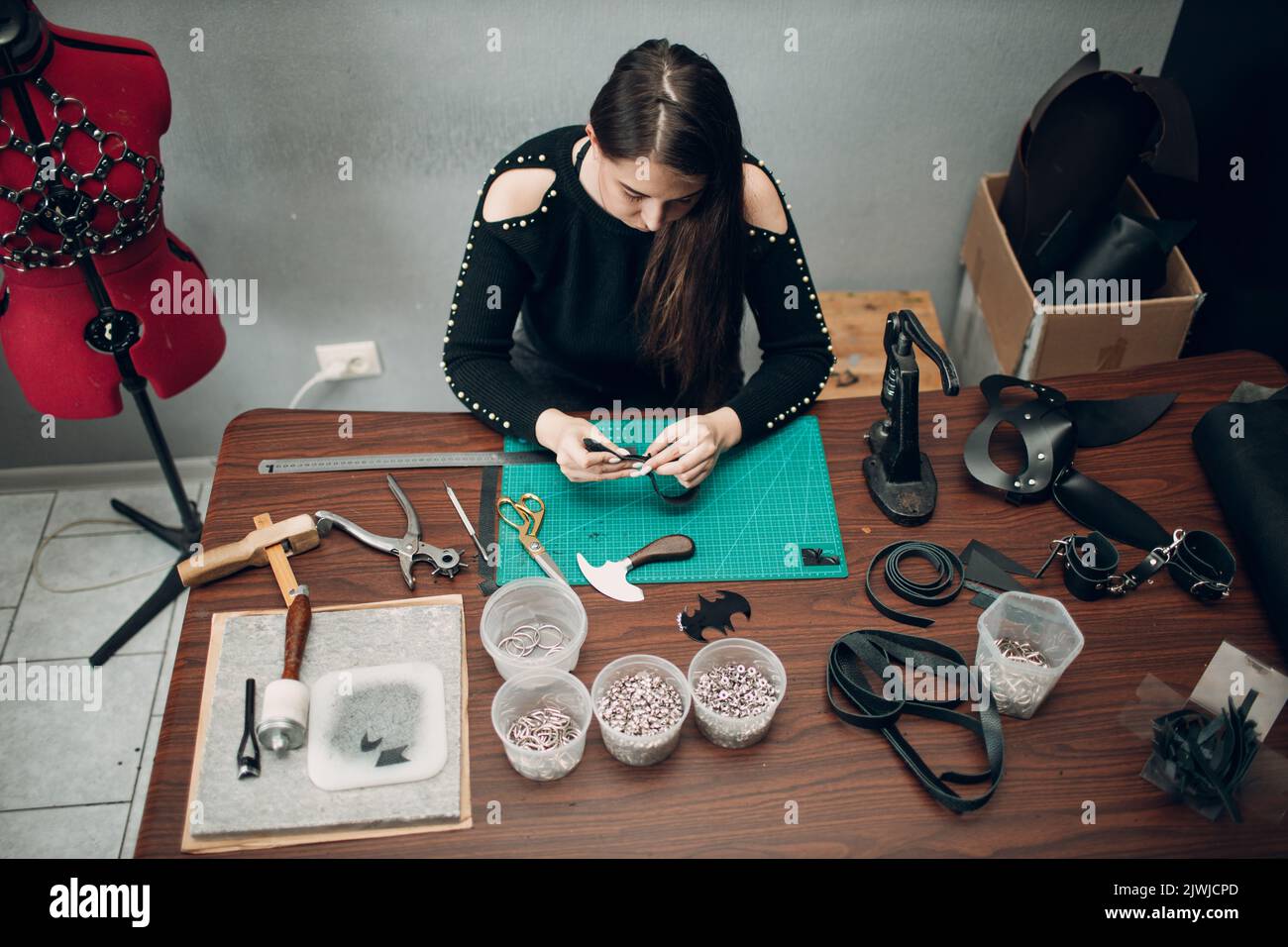 Tanner woman making leather harness belt goods on Working