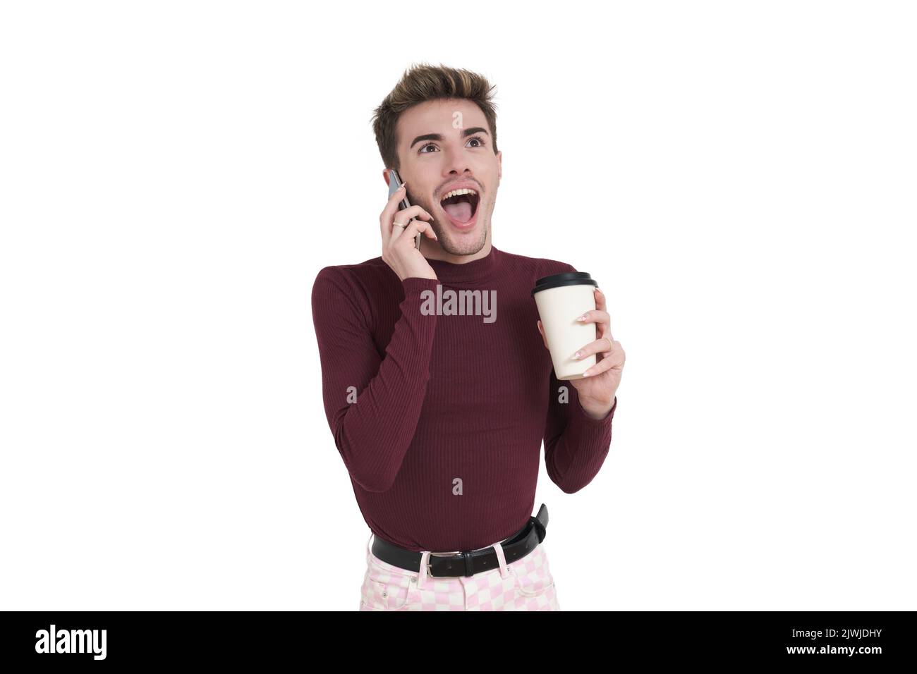 Young caucasian man excited speaking on the phone with a coffee cup, isolated. Stock Photo