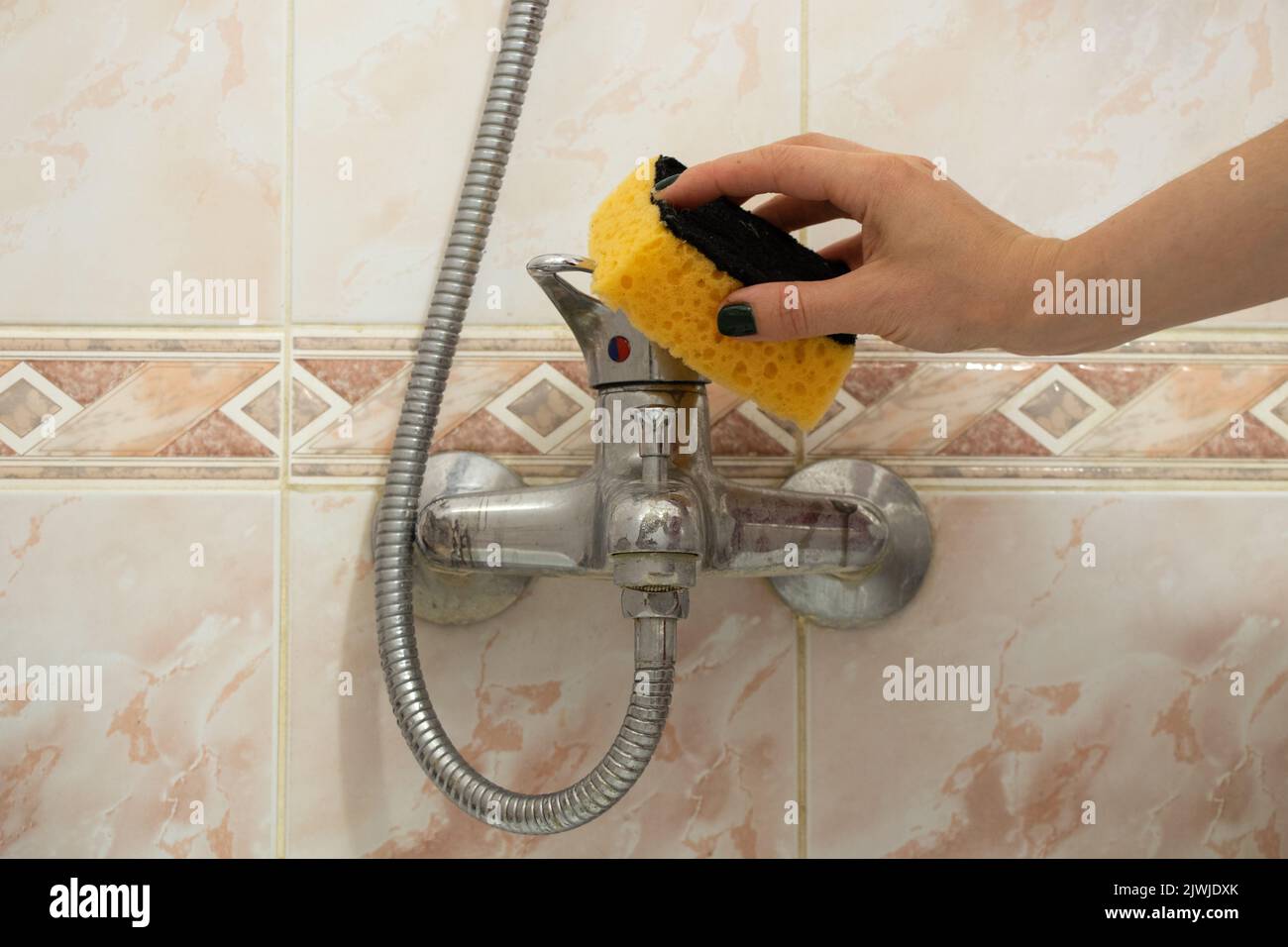 Female hand washes the faucet in the bathroom, cleaning and washing the