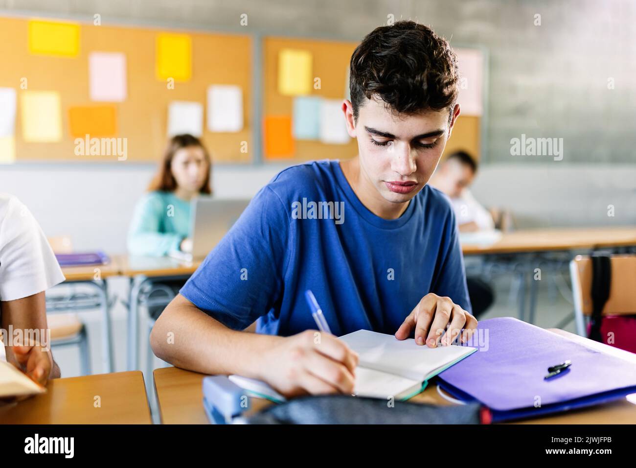 High school young student writing to notebook in class lecture Stock Photo