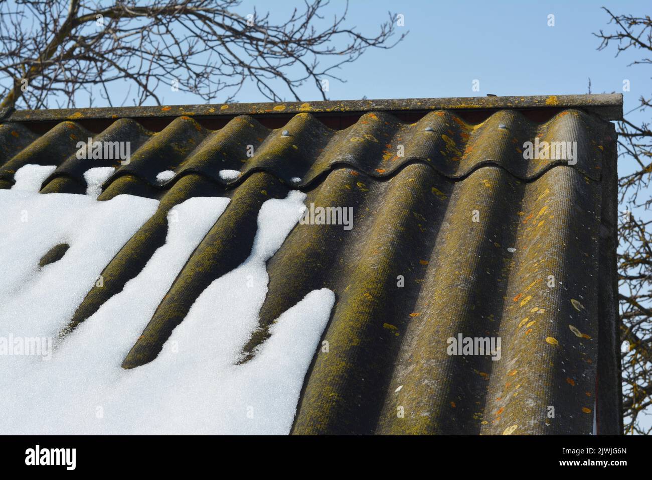 An old asbestos roof when snow is melting in spring. An asbestos roof