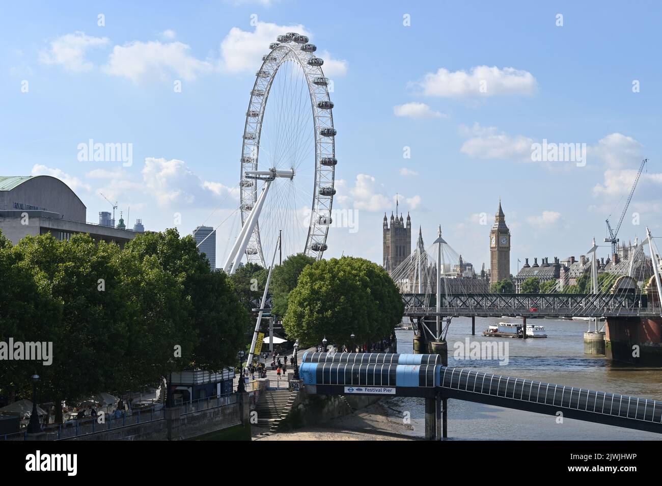 The London Eye on the south bank of the River Thames as seen from Waterloo Bridge with the Palace of Westminster in the background Stock Photo
