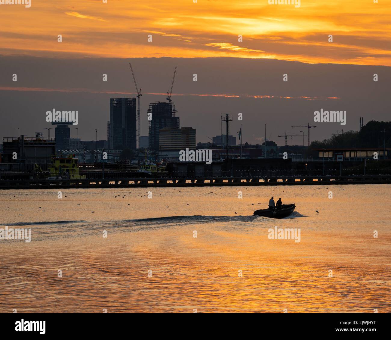 Sunset at the waterfront of Amsterdam, modern buildings in the center of Amsterdam in silhouette