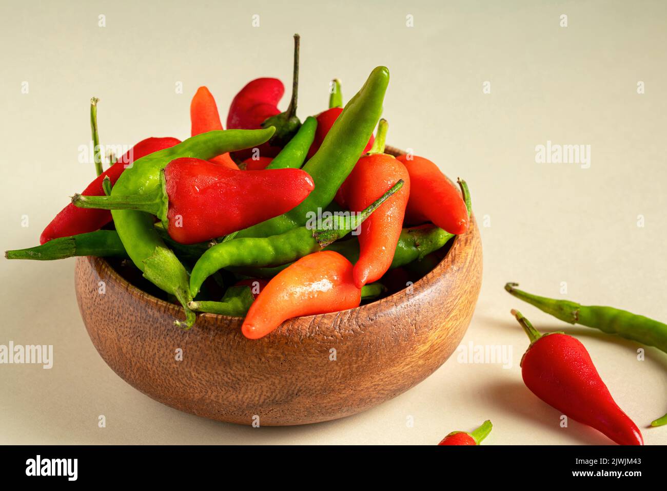 Organic fresh red and green hot peppers in wooden bowl Stock Photo
