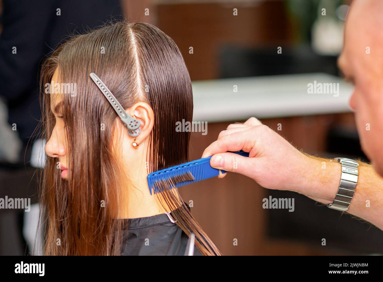 Hairdresser divides long hair into sections with the comb of a young
