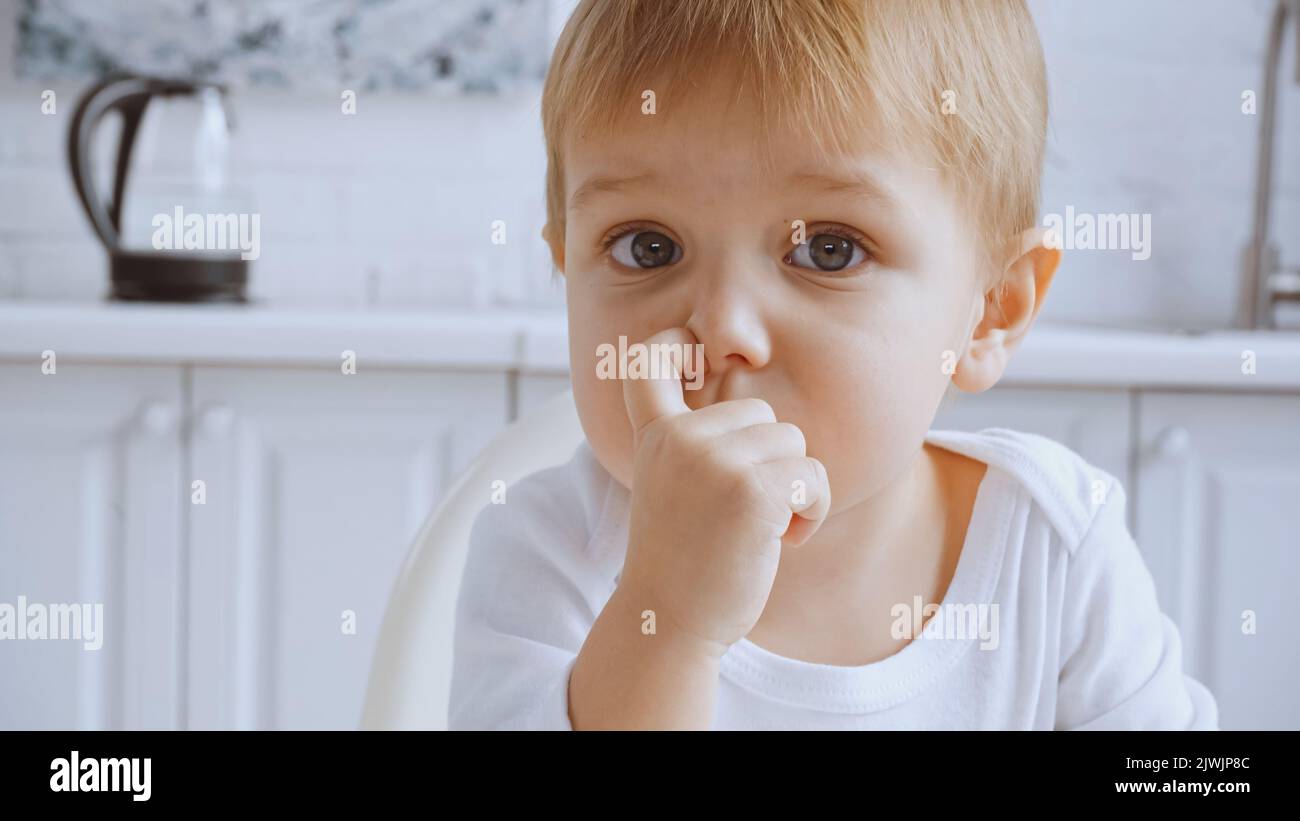 close up of toddler boy picking his nose and looking at camera at home Stock Photo