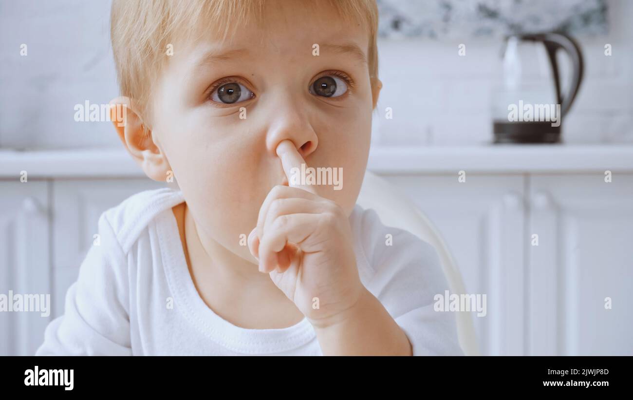 close up of toddler boy picking nose while looking at camera at home Stock Photo