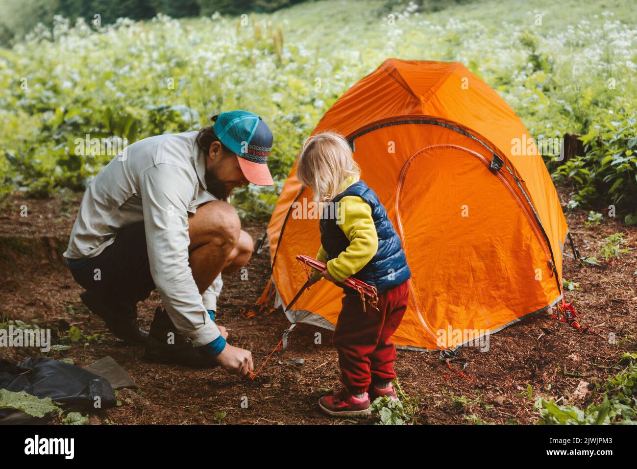 Camping family vacations child helps father to set tent travel
