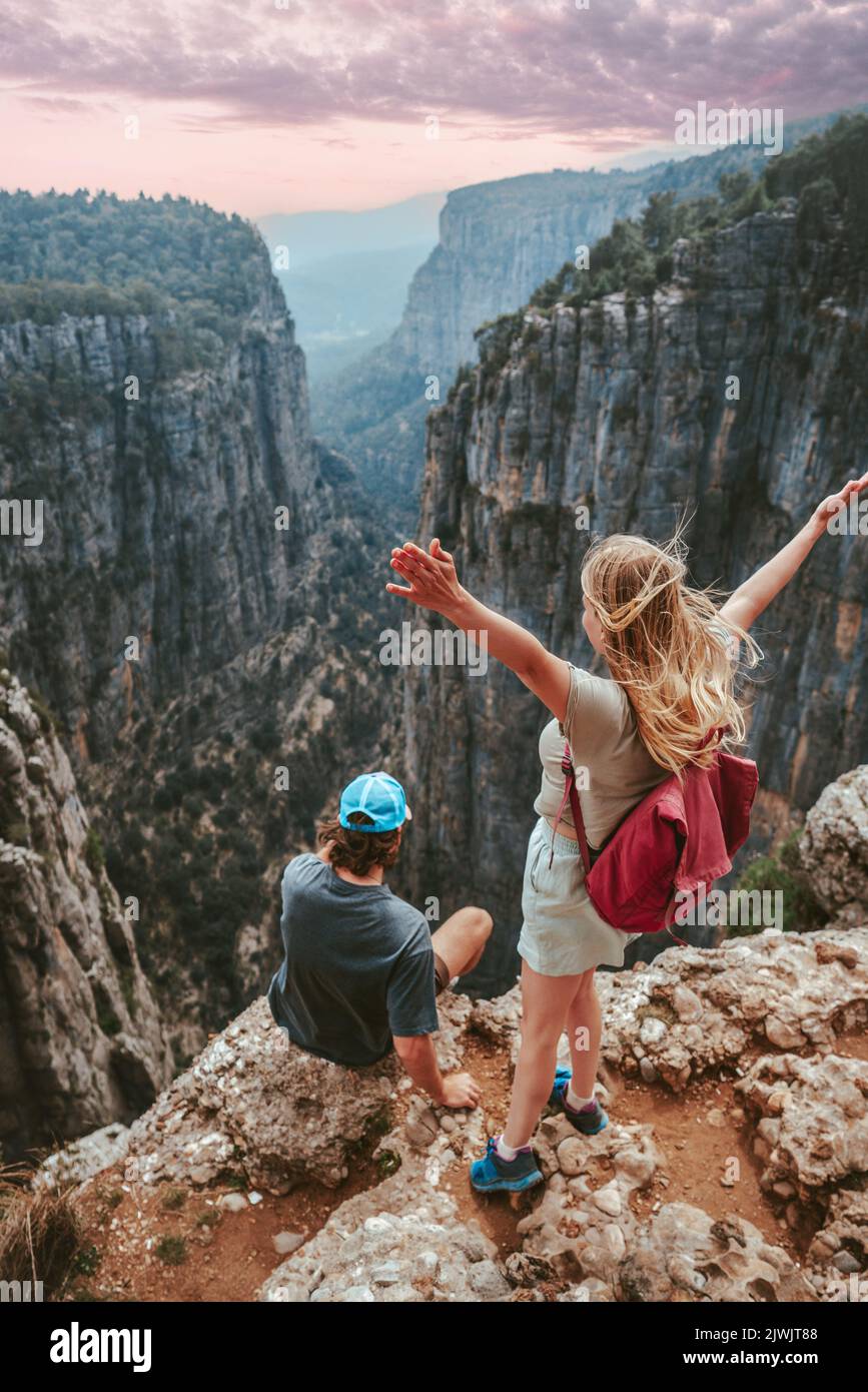 Couple on cliff Tazi canyon travel hiking together healthy lifestyle active summer vacations outdoor young man and woman tourists enjoying aerial view Stock Photo