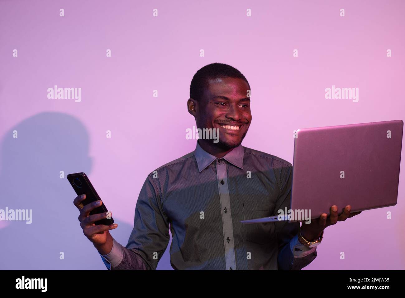 african man using a phone and laptop Stock Photo