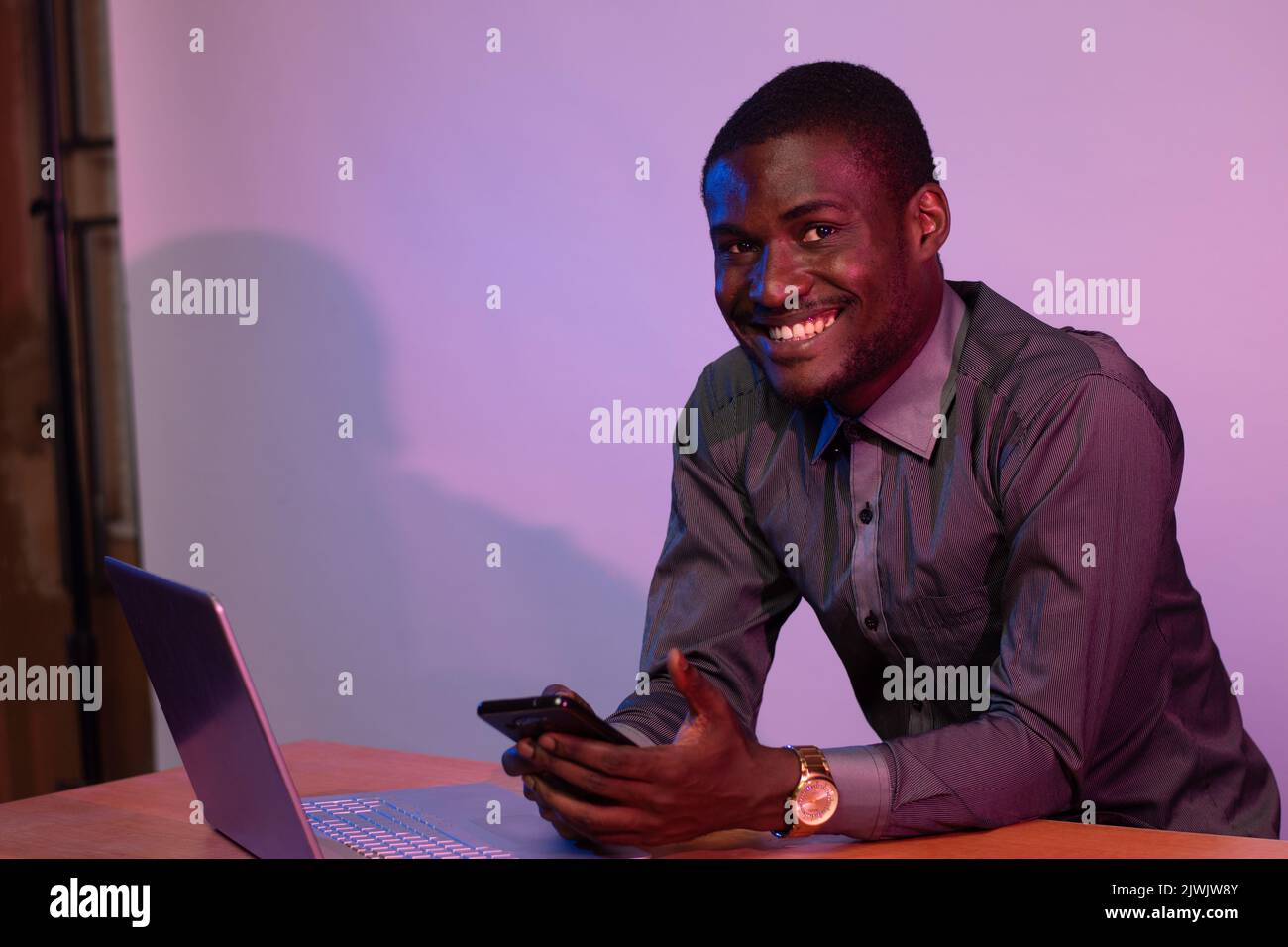 african man using his phone and laptop Stock Photo