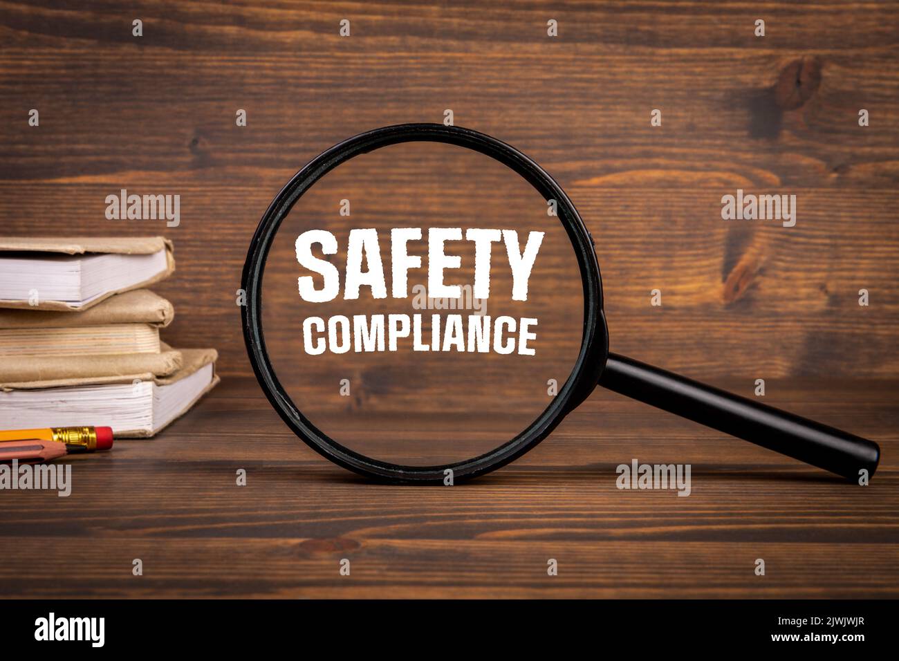 SAFETY COMPLIANCE concept. Magnifying glass on a dark wooden background. Stock Photo