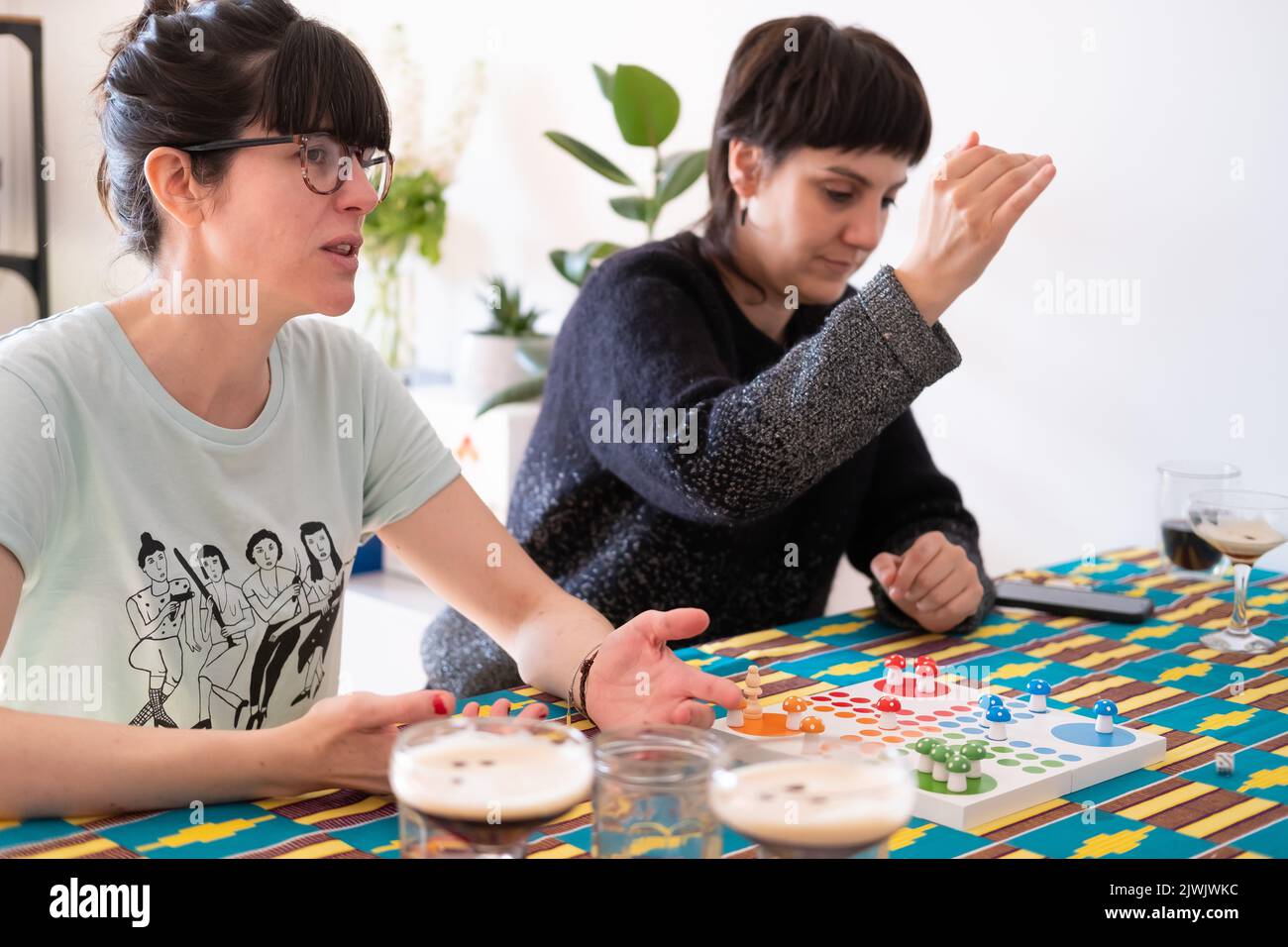 Female friends playing board games and having drinks at home Stock