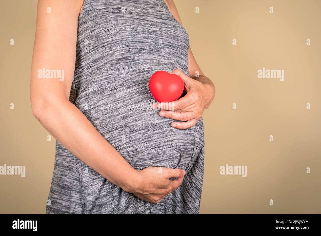 Pregnant woman with a red rubber heart in her hand. Love and family concept. Stock Photo