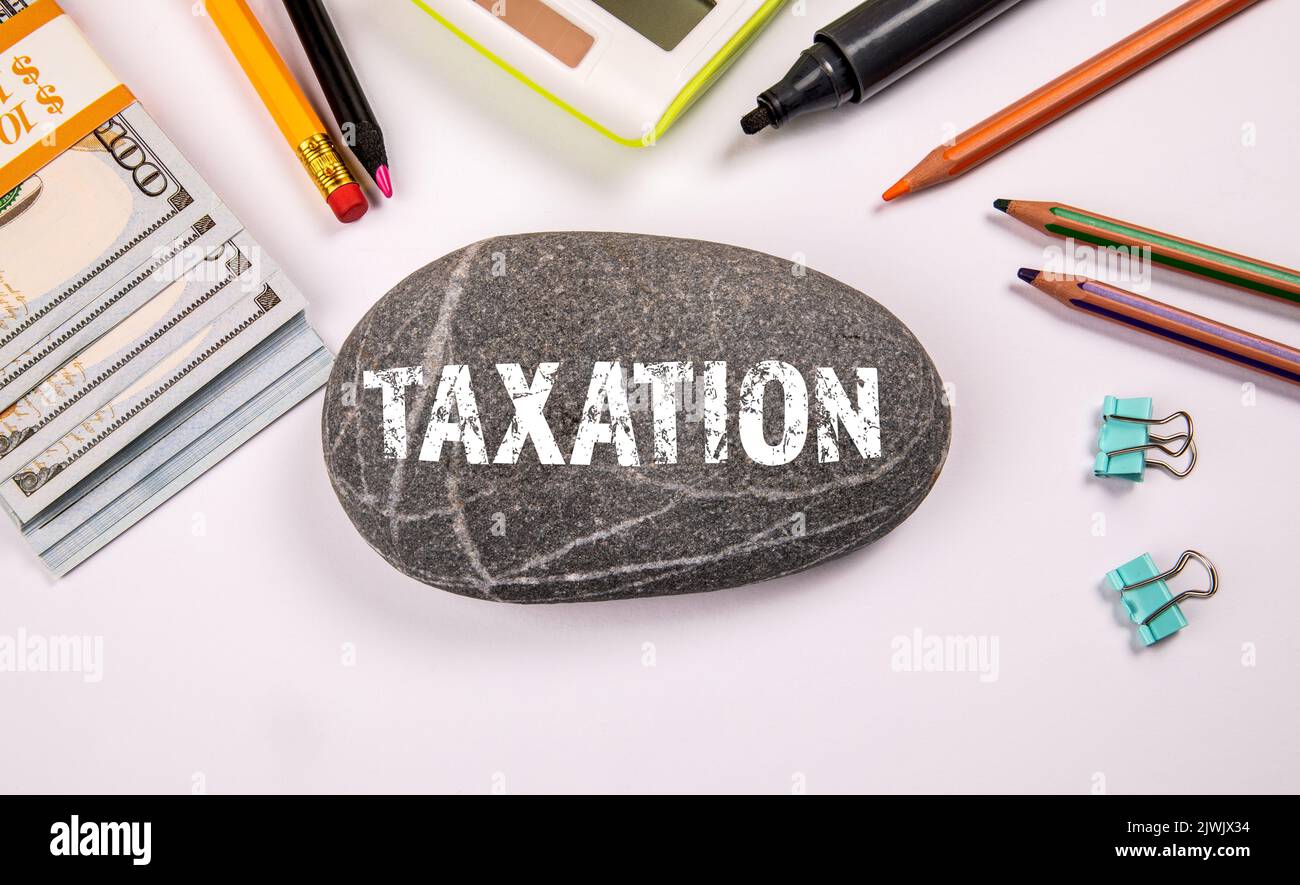 TAXATION. Text on stone. Stationery on the office table. Stock Photo