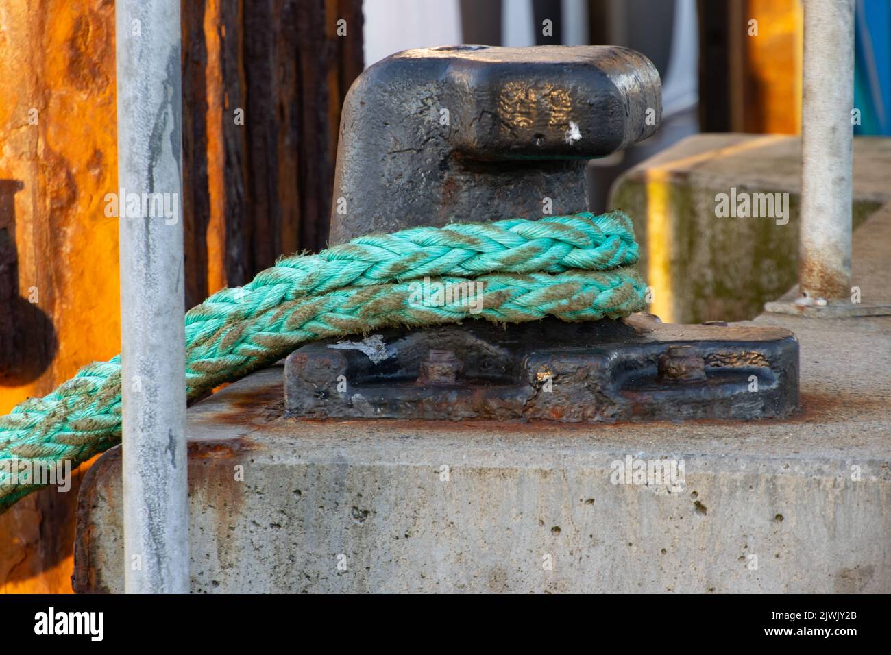 Green rope tied to a metal mooring bollard Stock Photo