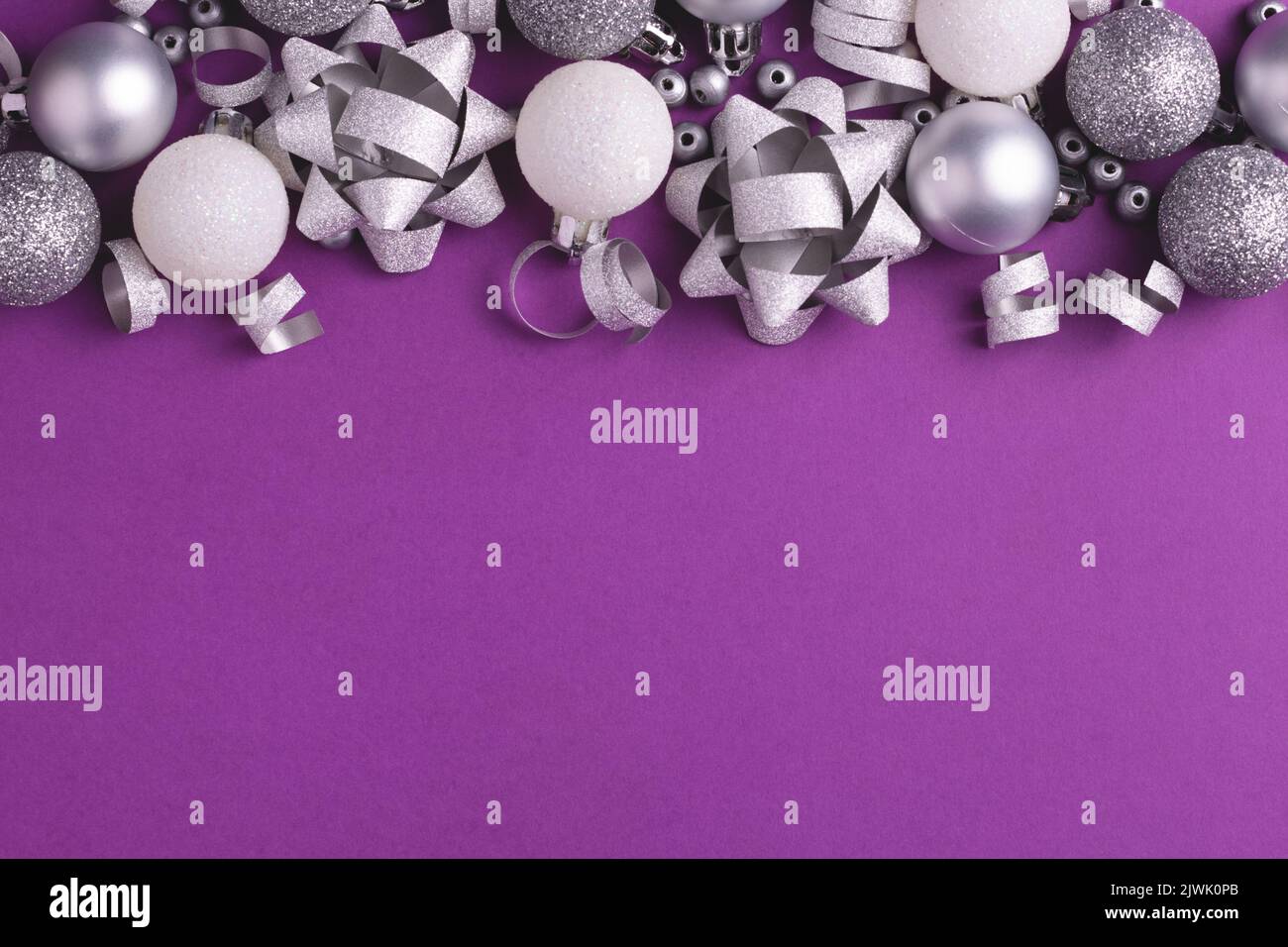Holiday background with grey and white metallic decorations on purple. Copy space. Christmas and New Year. Stock Photo