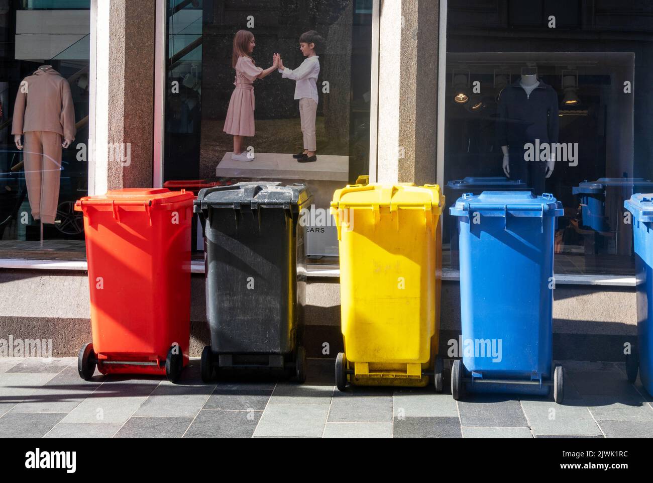 Red, black, yellow, and blue trash bins in Liverpool Stock Photo