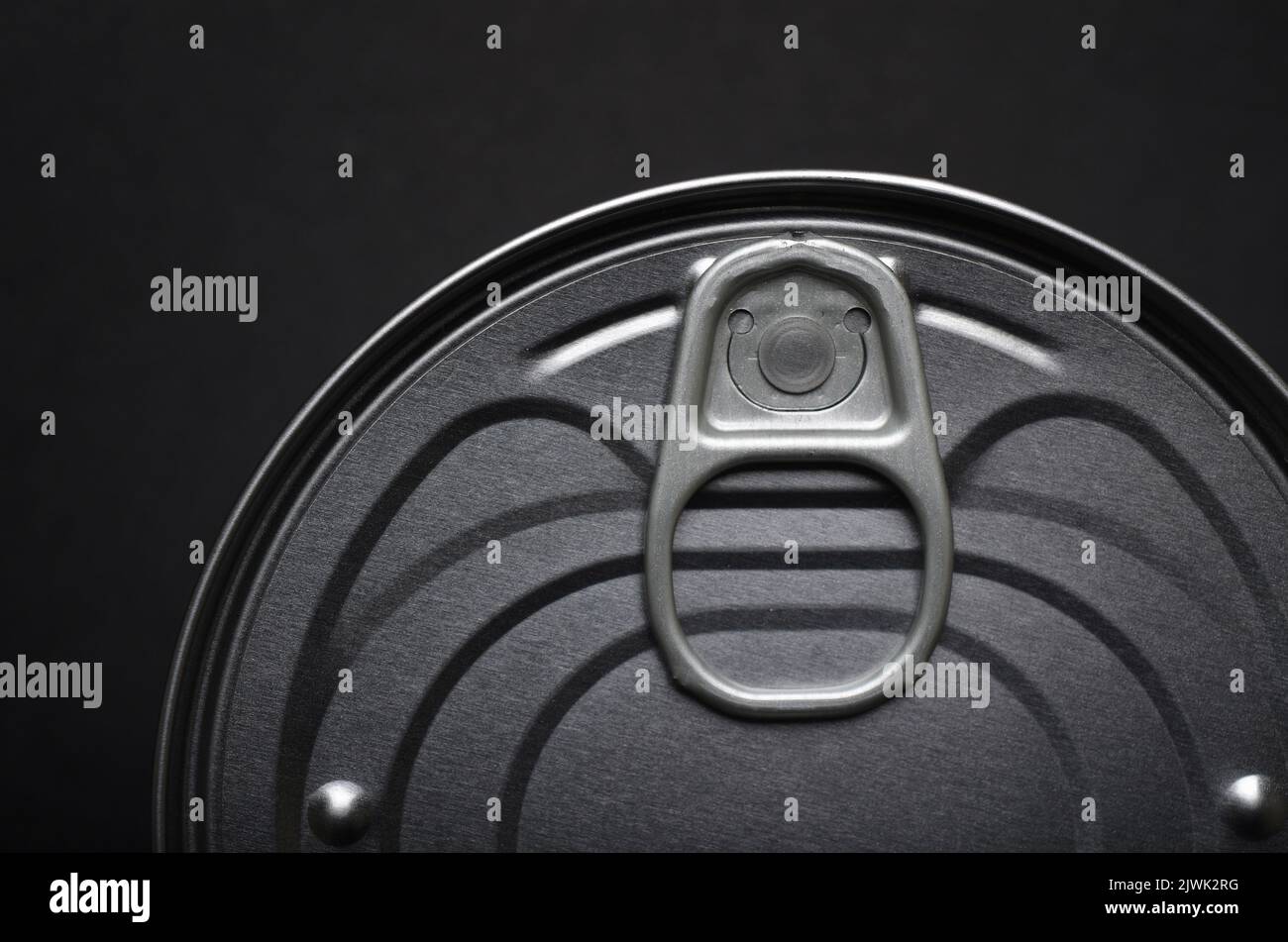 Top of tin can lid showing ring pull opener from above on black background Stock Photo