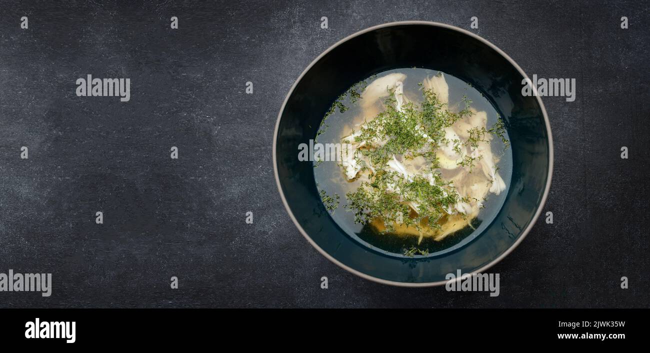 Transparent chicken broth with dill, consomme, on a dark background