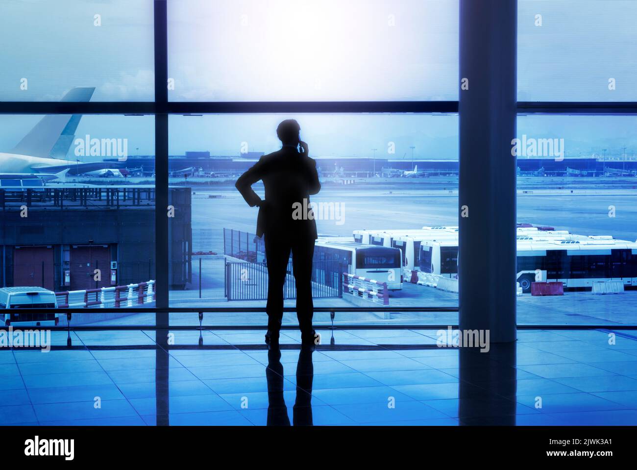 Businessman silhouette calling by phone in airport lobby in front of glass windows Stock Photo