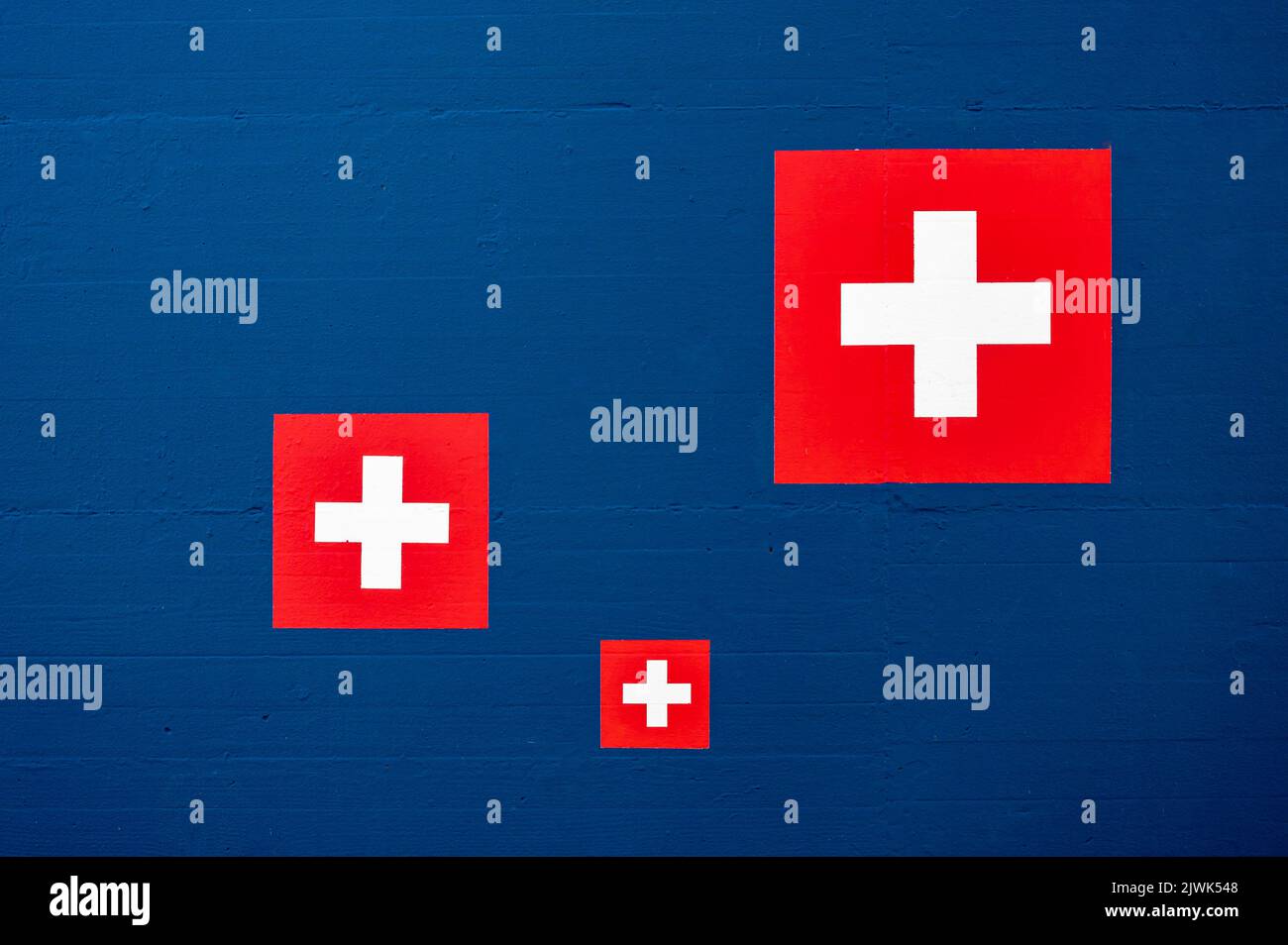 Swiss flag icon on blue wall. Abstract backgrounds. Copy space. Stock Photo