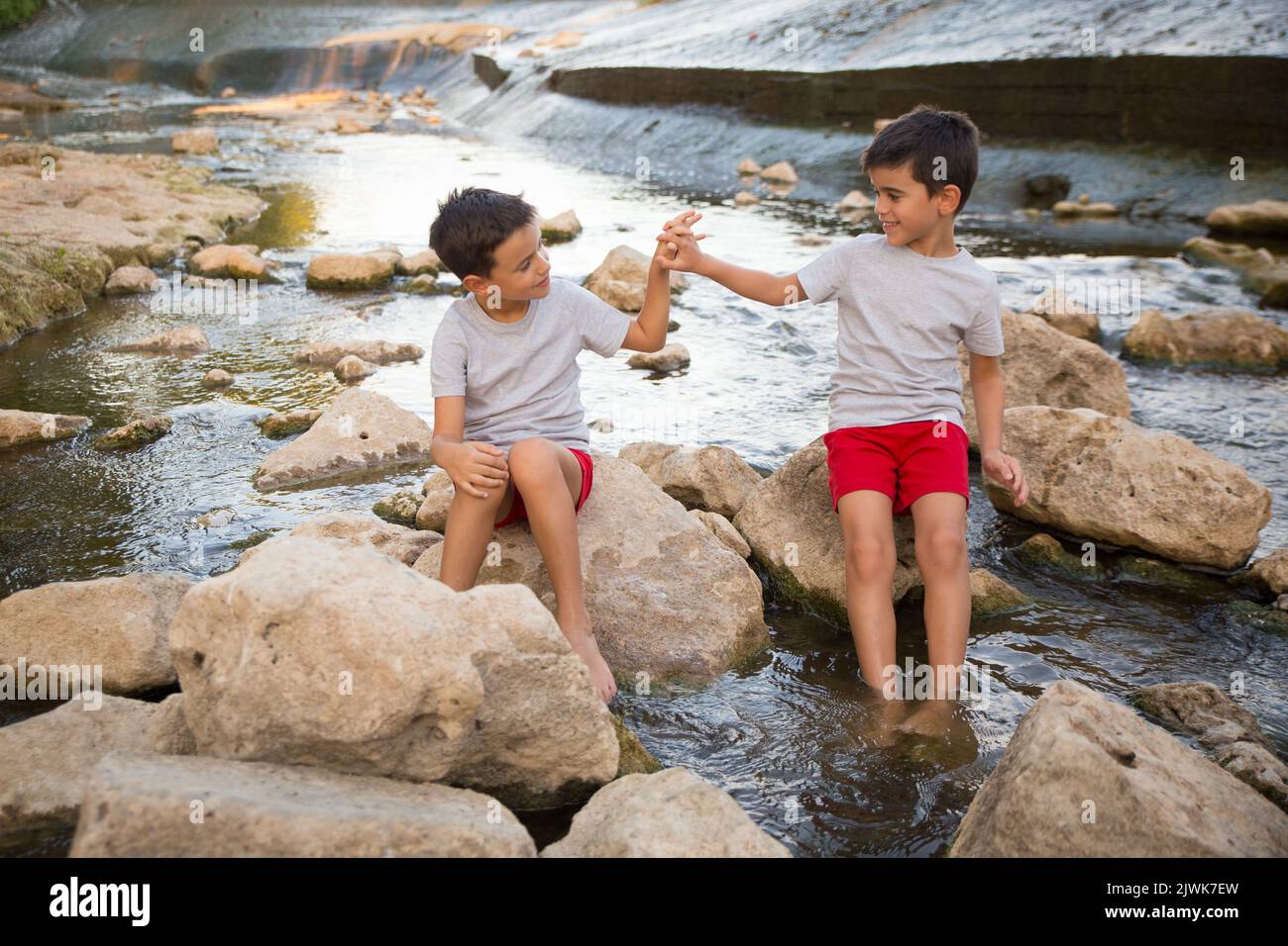 two brothers join hands while enjoying a day out on the river Stock Photo