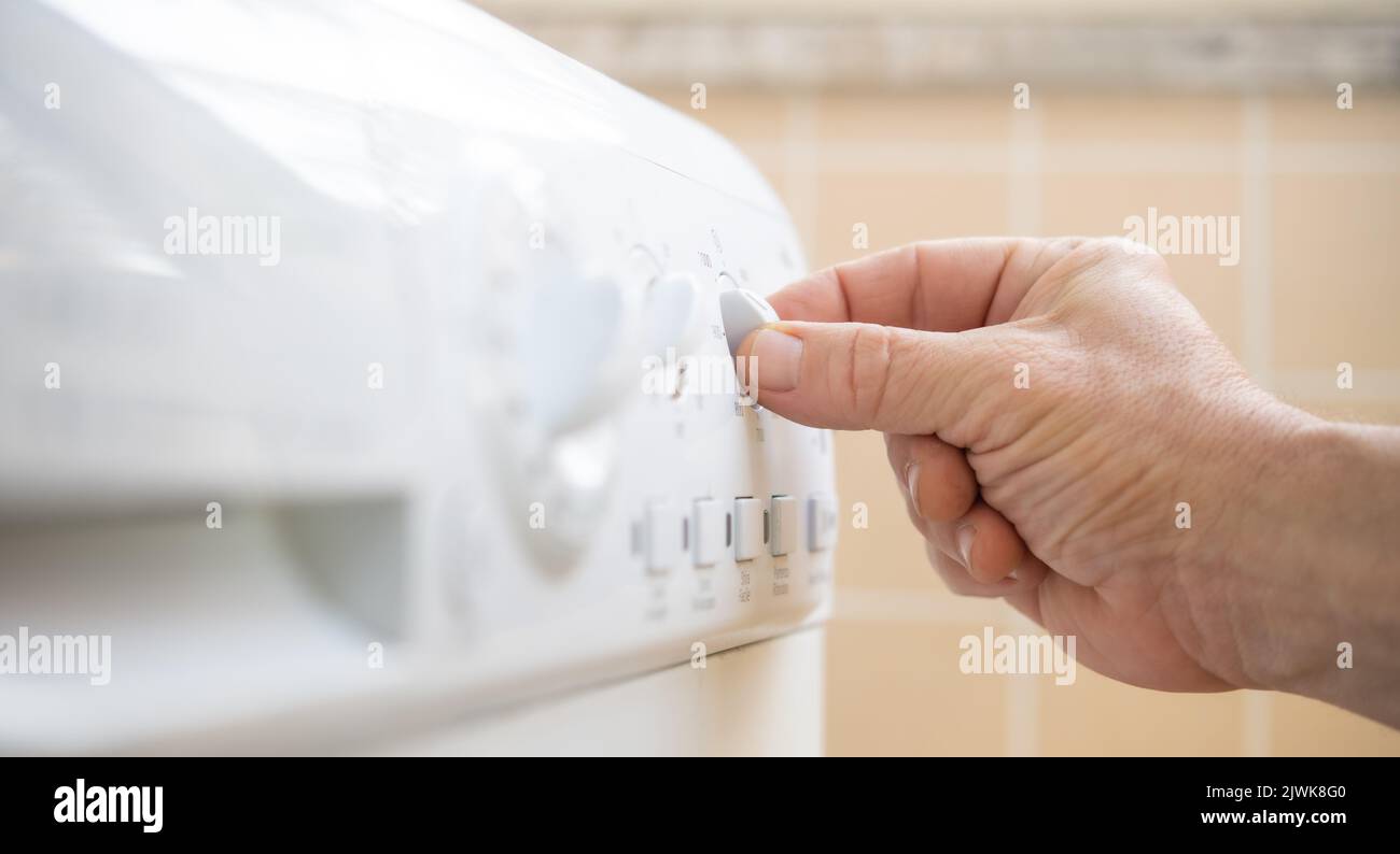 Household appliance saving energy, human hand tuning knob on machine control panel Stock Photo