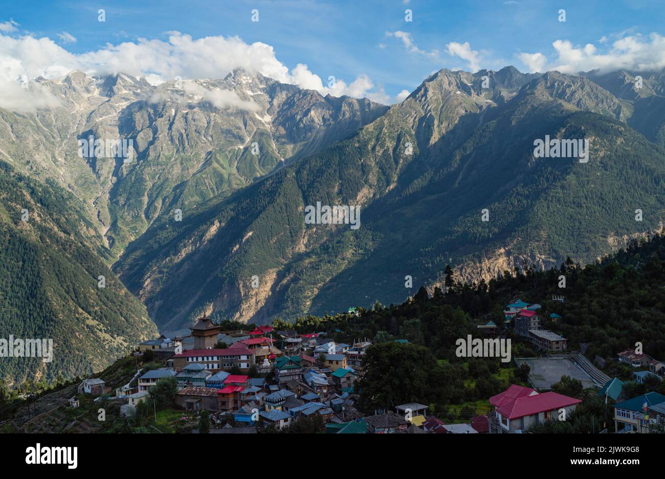 Elevated view of Kalpa village and Himalayas with sharp ridges as backdrop on a fine morning in summer in Kalpa, Himachal Pradesh, India. Stock Photo