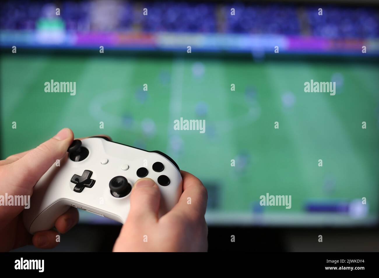Plays football on TV, holding white gamepad Stock Photo