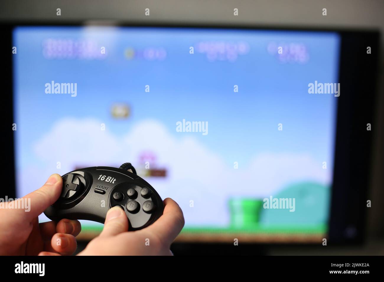 Plays a retro game on the TV while holding classic black joystick Stock Photo