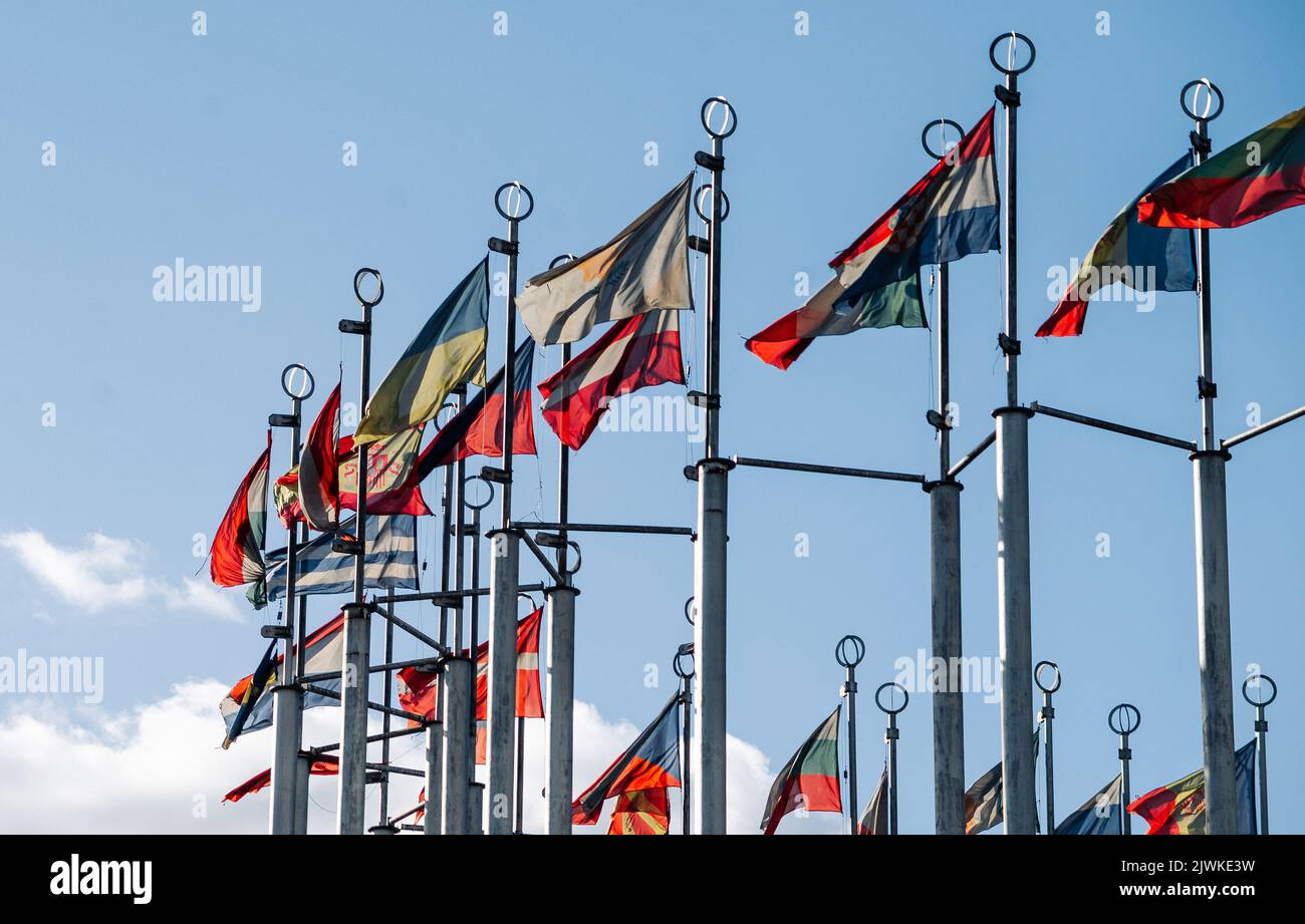 flags of the countries of the world on flagpoles against the blue sky ...