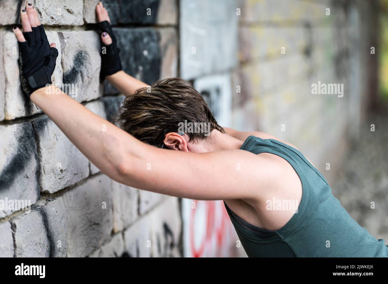 Portrait of a 36 year old white tired woman, stretching against a wall after a work out, Brussels, Belgium Stock Photo