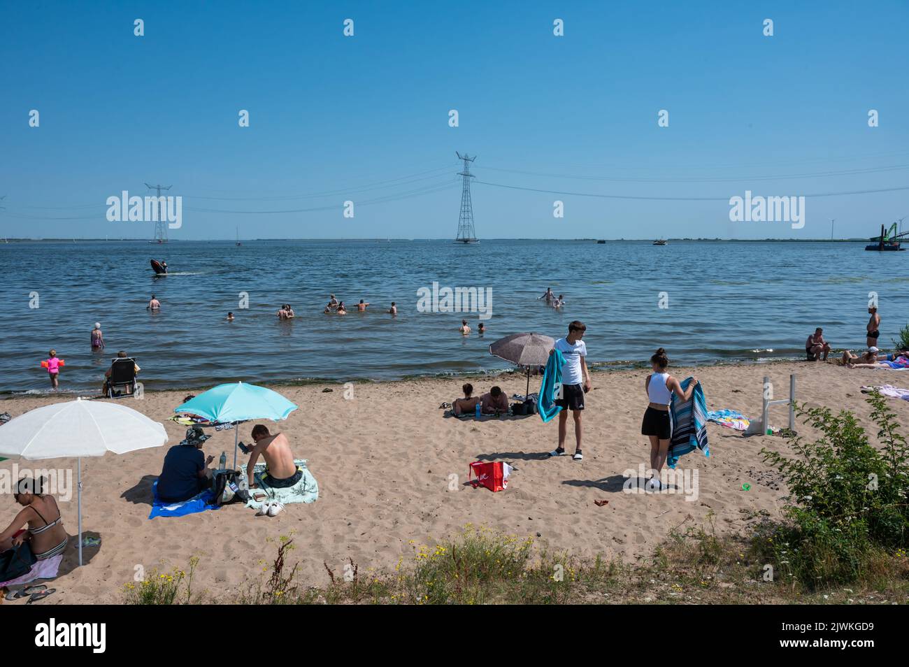 Nagele, Flevoland, The Netherlands - 07 20 2022 - Families at the Ketel beach with the blue lake in the background Stock Photo